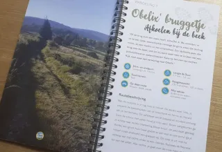 Una guida escursionistica con itinerario dal Camping Les Trexons a Grand Est, Francia, su un tavolo di legno.