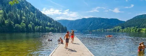 Bambini e famiglie si godono una giornata di sole su un lago vicino a Gerbépal, Grand Est, Francia, tra le montagne.