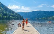 Children and families enjoy swimming on a sunny day by a peaceful lake near Gerbépal, Grand Est, France.