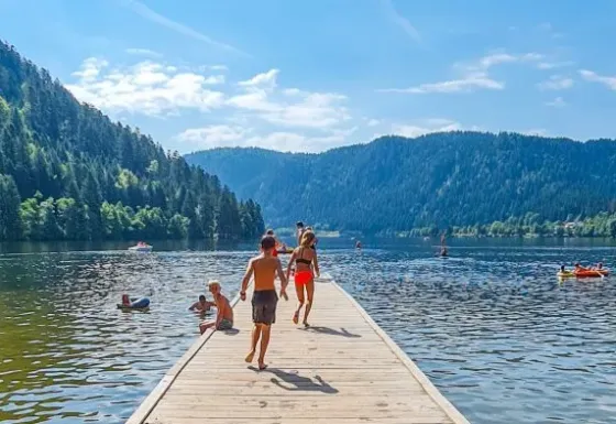 Bambini e famiglie si godono una giornata di sole su un lago vicino a Gerbépal, Grand Est, Francia, tra le montagne.