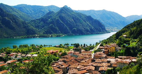 Panorama di Idro in Lombardia, Italia, con case dai tetti rossi, lago cristallino e montagne verdi circostanti.