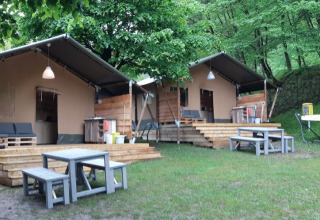 Due tende glamping con terrazze e tavoli da picnic al Campeggio Belvedere, Lombardia, Italia, immerse nel verde.