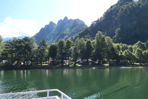Vista sul lago, sugli alberi e sulle montagne dal campeggio Belvedere, parco vacanze in Lombardia, Italia.