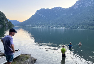 Uomo e bambini al lago con montagne al campeggio Belvedere nel parco vacanze in Lombardia, Italia.