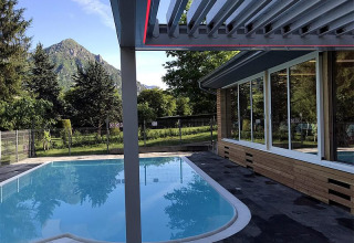 Piscina all'aperto al Campeggio Belvedere, Lombardia, Italia, con vista monti e vegetazione rigogliosa.