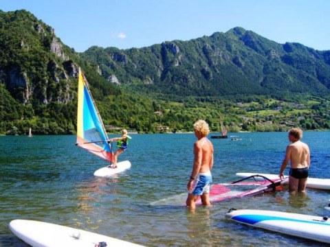 Persone che fanno windsurf al Campeggio Belvedere, Lago e montagne della Lombardia, Italia sullo sfondo.
