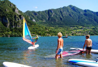 Persone che fanno windsurf al Campeggio Belvedere, Lago e montagne della Lombardia, Italia sullo sfondo.