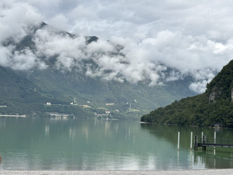 Vista sul lago e sulle montagne dal campeggio Belvedere in Lombardia, Italia, con cielo nuvoloso.