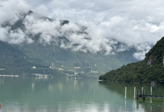 Vista sul lago e sulle montagne dal campeggio Belvedere in Lombardia, Italia, con cielo nuvoloso.