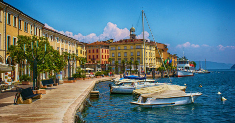 Lungolago pittoresco con barche e edifici colorati a Idro, in Lombardia, Italia, in una giornata di sole.