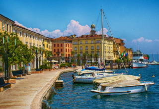 Lungolago pittoresco con barche e edifici colorati a Idro, in Lombardia, Italia, in una giornata di sole.