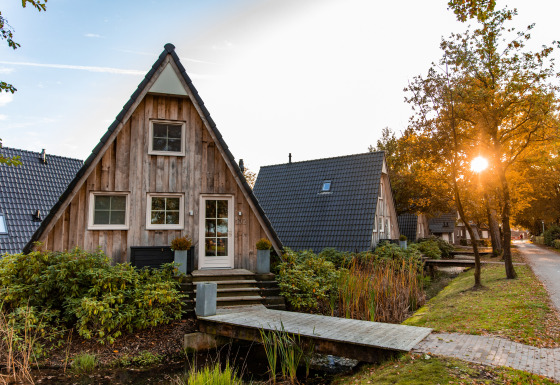 Salida del sol en Wellness Lodge, una pequeña casa triangular de madera rodeada de jardín y sendero.