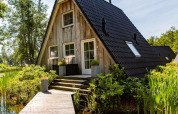 Casa pequeña tipo A Wellness Lodge en Hof van Salland, rodeada de vegetación y un estanque en Holanda.