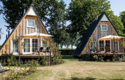 Dos casas tiny house Wellness Lodge con fachada de madera y terrazas en Hof van Salland, Países Bajos.