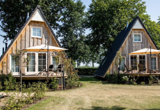 Dos casas tiny house Wellness Lodge con fachada de madera y terrazas en Hof van Salland, Países Bajos.