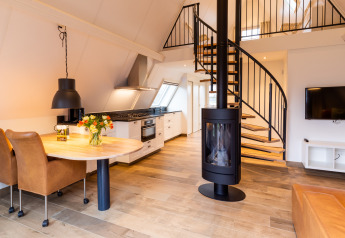 Modernes Tiny House Wellness Lodge bei Hof van Salland, Niederlande, mit Küche, Kamin und Wendeltreppe.