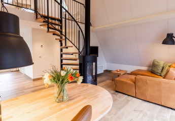 Gemütlicher Wohnbereich in der Wellness Lodge mit Ledersofa, Kamin und Wendeltreppe, Hof van Salland.