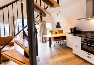 Interior moderno de tiny house con escalera de caracol y cocina en Wellness Lodge en Hof van Salland, Países Bajos.
