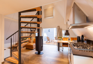 Interior luminoso y moderno de la Wellness Lodge con escalera de caracol, cocina y sala en Hof van Salland.