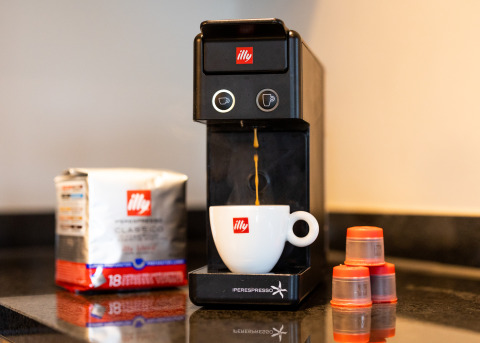 Koffiemachine met illy-capsules en kopje op het aanrecht in een glampingaccommodatie, klaar voor gebruik.