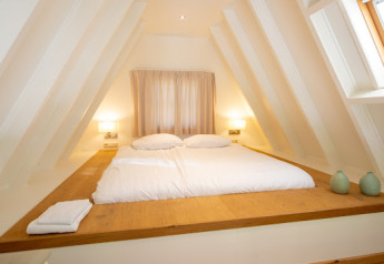 Gemütliches Schlafzimmer in der Wellness Lodge im Hof van Salland, Niederlande, mit Doppelbett und sanftem Licht.