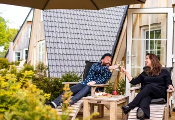 Paar genießt Wein und Snacks auf der Terrasse vor einer Wellness Lodge im Hof van Salland, Niederlande.