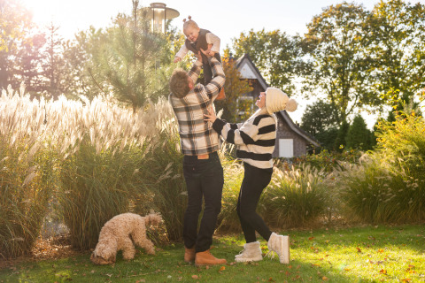 Una familia juega con su hijo en el jardín de Wellness Lodge en Hof van Salland, Países Bajos, en un día soleado.