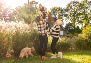 Una familia juega con su hijo en el jardín de Wellness Lodge en Hof van Salland, Países Bajos, en un día soleado.