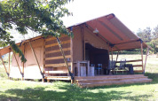 Tienda safari en Campsite Podere sei Poorte en Italia con terraza de madera, asientos exteriores y naturaleza verde.