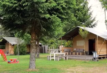 Safaritent in een natuurlijke omgeving met speeltuin en bomen, ideaal voor gezinnen en ontspanning.