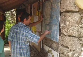 Folk studerer et kort over Domaine de Pradines feriepark i Occitanie, Frankrig, ved opslagstavle udendørs.