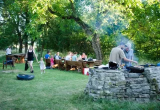 Eine Gruppe Menschen genießt ein sommerliches Grillfest im Grünen im Domaine de Pradines, Frankreich.