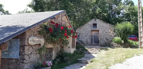 Edifici in pietra con fiori e insegna reception al Domaine de Pradines, parco vacanze in Occitanie, Francia.