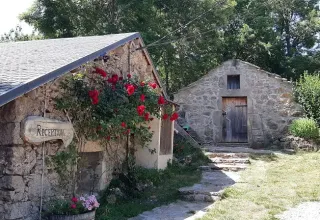 Stenbygninger med blomster og reception skilt på Domaine de Pradines, feriepark i Occitanie, Frankrig.