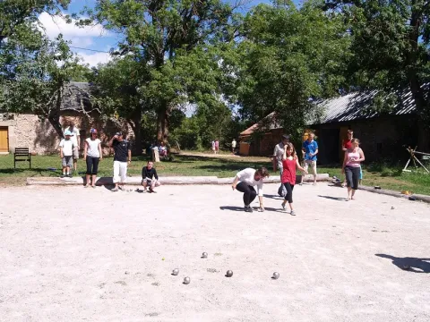 People play pétanque outdoors at Domaine de Pradines holiday park in Occitanie, France, on a sunny day.