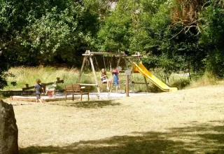 Des enfants jouent sur une aire de jeux avec balançoires et toboggan au Domaine de Pradines, Occitanie, France.