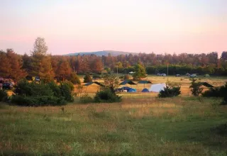 Tramonto al Domaine de Pradines, parco vacanze in Occitania, Francia, con tende immerse nel verde.