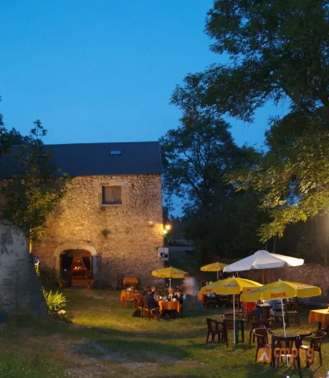 Ambiance du soir près d’un bâtiment en pierre et terrasse au Domaine de Pradines, Occitanie, France.