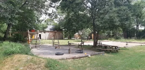 Aire de jeux au Domaine de Pradines avec balançoires, bac à sable et tables de pique-nique en Occitanie.