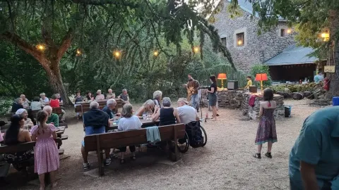 Noche en Domaine de Pradines, Occitania, Francia, con personas cenando al aire libre y música en vivo.
