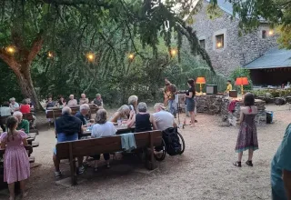 Avondscene op Domaine de Pradines, Occitanië, Frankrijk, met mensen die buiten dineren en livemuziek.