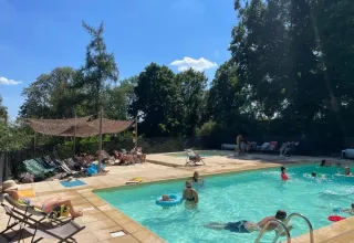 Outdoor swimming pool at Domaine de Pradines, Occitanie, France, with guests relaxing and enjoying the sun.