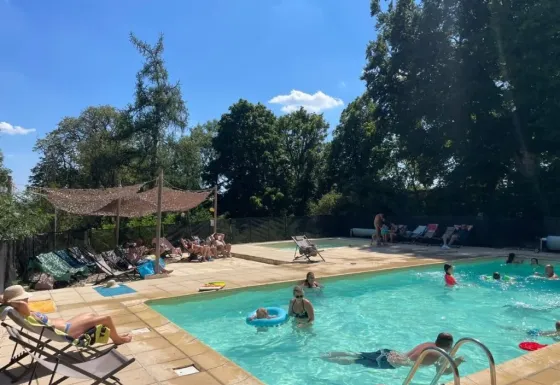 Piscina exterior en Domaine de Pradines, Occitania, Francia, con huéspedes relajándose y nadando.