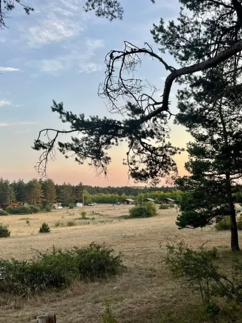 Vista panorámica de Domaine de Pradines en Occitanie, Francia, con árboles, cabañas y prados abiertos al fondo.
