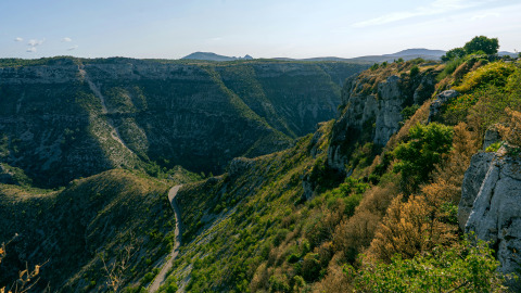 Felsige Schlucht mit bewachsenen Hängen bei Lanuéjols in Okzitanien, Frankreich, an einem sonnigen Tag.