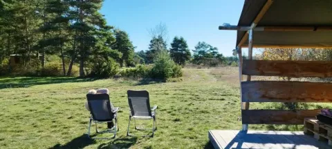 Udsigt fra en safaritelt ved Domaine de Pradines, med to stole og grøn natur under en blå himmel.