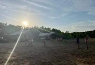 Børn leger foran en safaritelte ved Domaine de Pradines i Frankrig under solnedgangen på en åben mark.