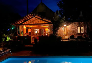 Cabina illuminata accanto alla piscina di notte al campeggio Mas du Midi, villaggio turistico in Occitania, Francia.