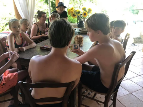 Bambini e adulti giocano a carte insieme a un tavolo al campeggio Mas du Midi, in Occitania, Francia.