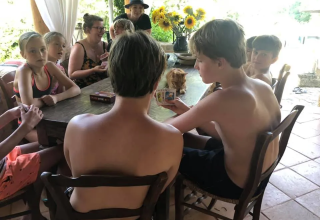 Bambini e adulti giocano a carte insieme a un tavolo al campeggio Mas du Midi, in Occitania, Francia.